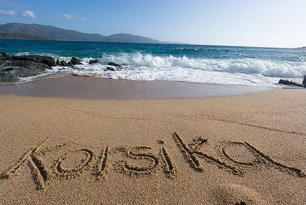Korsika am Strand in den Sand geschrieben mit Blick auf das Meer