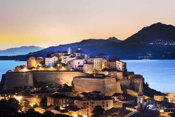 Blick auf die im Abendlicht beleuchtete Zitadelle von Calvi auf Korsika