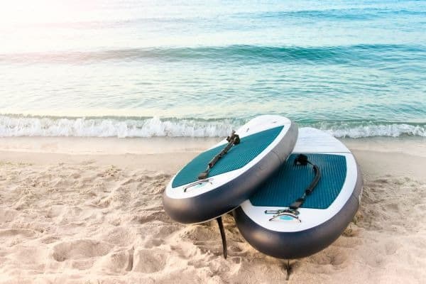 Zwei SUP-Boards liegend am Strand an der Wasserkante