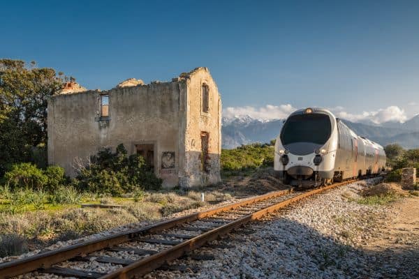 Zug fährt vorbei an einem verlassenen Bahnhof bei Lumio auf Korsika