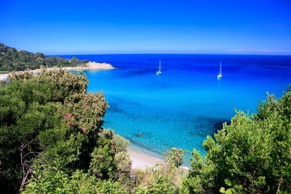 Traumhafte Bucht von Canella auf Korsika mit türkisblauem Meer, Sandstrand und 2 weißen Seegelbooten