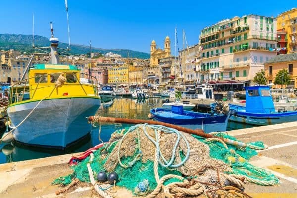 Traditionelle bunte Fischerboote und Netze im Hafen von Bastia auf Korsika