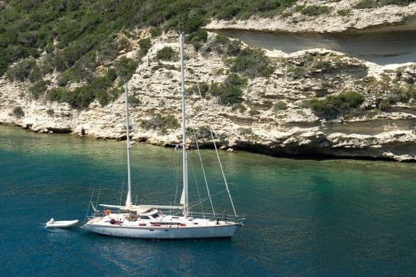 Weißes Segelboot in einer Bucht vor Bonifacio auf Korsika